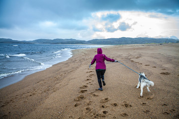Woman and her Siberian Husky on the beach at low tide. Shore of the Barents Sea