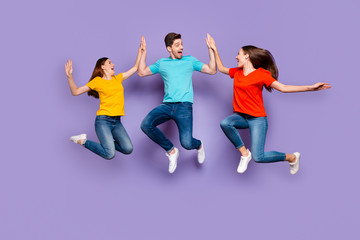 Fototapeta na wymiar Full length body size photo of three excited glad optimistic delightful millennial generation group in blue yellow outfit having fun and good mood isolated violet background