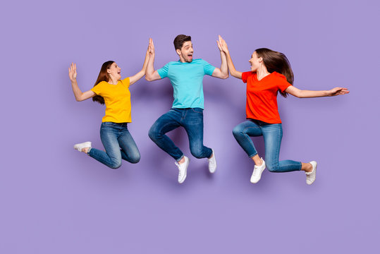 Full length body size photo of three excited glad optimistic delightful millennial generation group in blue yellow outfit having fun and good mood isolated violet background