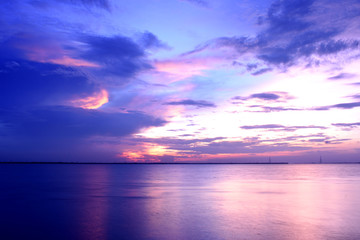 the sun is about set making the sky beautiful with its vibrant hues .