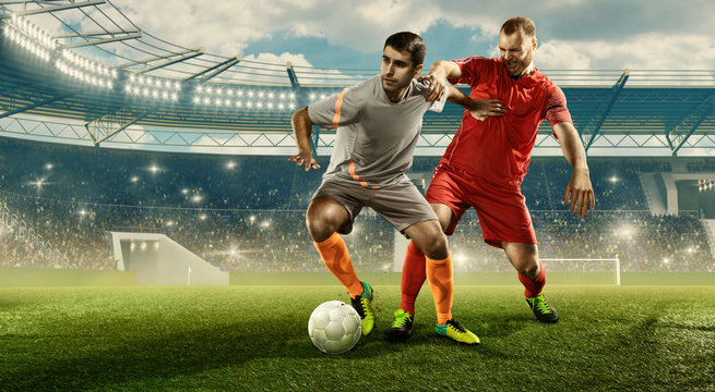 Two Professional Soccer Players Fight For The Ball During The Game. Stadium With Cheering Fans