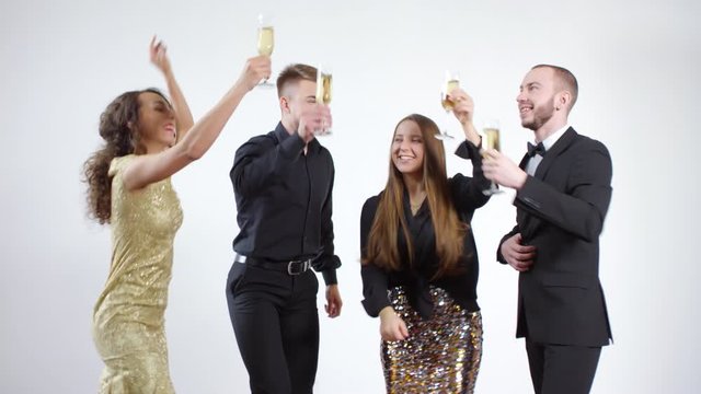 Slowmo shot of happy young men and women clinking glasses of champagne and dancing isolated on grey backgroundSlowmo shot of happy young men and women clinking glasses of champagne and dancing isolate