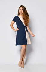 Luxurious curly female model in a two-tone dress and a full-length stilettos. Lovely girl in...