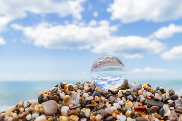 Fototapeta na wymiar Glass round ball on the beach reflects the sea in summer