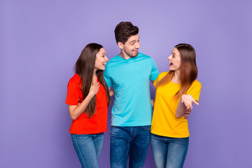 Portrait of nice attractive lovely charming cheerful cheery funny friendly guys wearing colorful t-shirts jeans denim spreading rumours isolated over violet lilac background