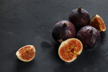 Figs and slices of figs on a dark gray background. Dark food photography.