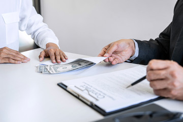 Bribery and corruption concept, bribe in the form of dollar bills, Businesswoman giving money while making deal to agreement a real estate contract and financial