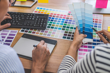 Two colleagues creative graphic designer working on color selection and drawing on graphics tablet at workplace, Color swatch samples chart for selection coloring