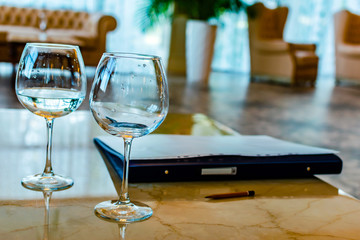 Two glasses of wine on the table hotel. Folder for pencil papers. The concept of business negotiations, meeting, collaboration.