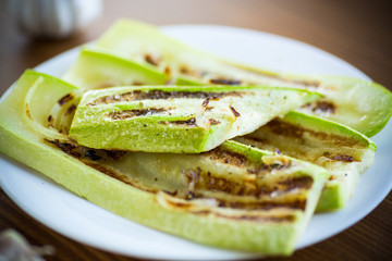 grilled zucchini with onions in a plate, on a table.