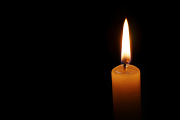 Dramatic burning candle flame on a black background with copy space