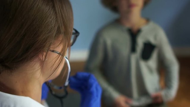Wheezing in the lungs, prevention of complications after viral infections, flu and SARS. Close-up of a female pediatrician listening to a baby's lungs using a phonendoscope
