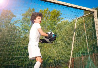 Soccer goalkeeper child in action. Young boy goalie holding a soccer ball as he stands in the goals on an soccer field preparing to throw the ball