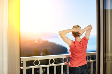 a slender girl stands in the morning on the balcony with beautiful views of the sea and mountains