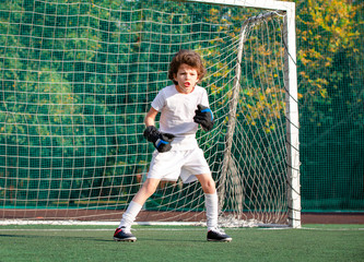 Young goalkeeper on an outdoor court standing in the football gate. Football, soccer player. Goalkeeper waits to catch the ball.