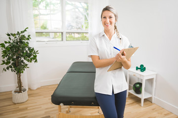 Young physiotherapist with clipboard in rehabilitation center