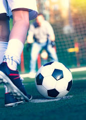 Little boy with his dad playing football on soccer pitch. kid football player prepairing to take a shot on a field. Young goalkeeper on an outdoor court standing in the football gate.