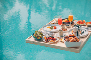 Breakfast in swimming pool, floating breakfast in tropical resort. Table relaxing in calm pool...