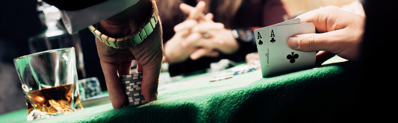 panoramic shot of man touching playing cards and poker chips near player - Powered by Adobe