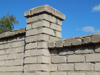 Old brick fence. Old fortified wall of gray brick.