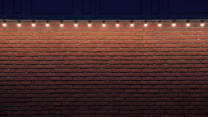 An orange brick wall with small light bulbs. Gradient stone background with low light and copy space. Place for advert. Wide web format photo.