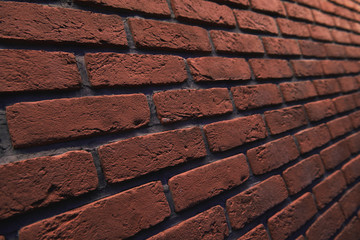 An orange brick wall at an angle with bokeh. Stone blurred background. Closeup.