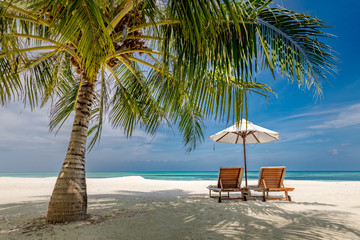 Beach landscape, chairs and umbrella next to palm tree on white sand. Peaceful tropical nature landscape. Calmness beach, luxury vacation and travel concept