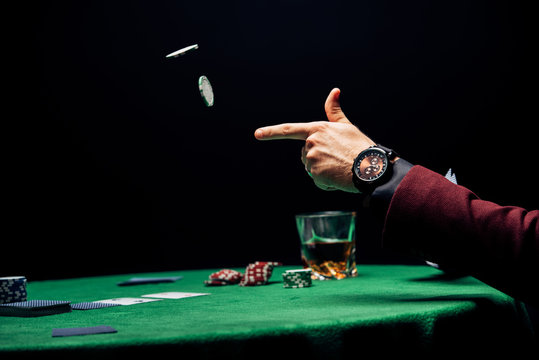 cropped view man throwing in air poker chips isolated on black