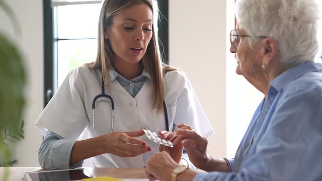 Nurse giving medication to elderly woman
