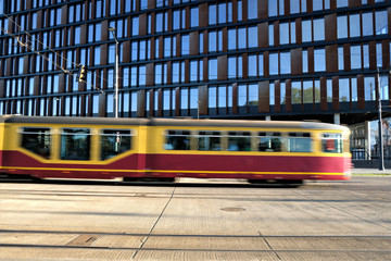 09/22/2019 Lodz, Poland, Yellow tram in motion in the street outside modern office building 'city...