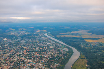 Fototapeta premium Top view of the evening city in fog, river, fields and forest