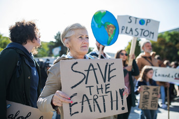 Senior with placard and poster on global strike for climate change.