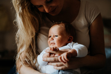 A beautiful young mother with a newborn baby at home.