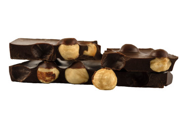 Pieces of chocolate with hazelnuts on a white background. Macro