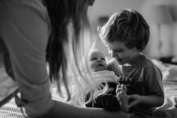 A beautiful young mother with a newborn baby and his brother at home.