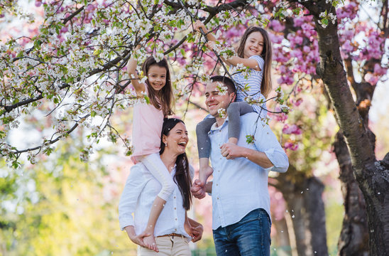 Young parents with small daugthers standing outside in spring nature.