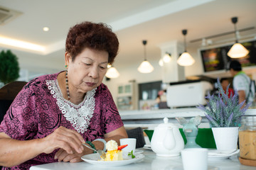 Obraz na płótnie Canvas Asian senior woman stawberry cheese cake in cafe.