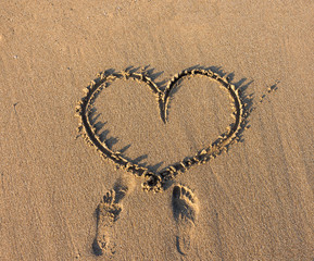 Heart sign writing on sand at the sunset.