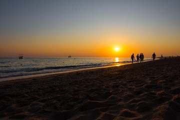 Silhouettes of people at sunset on the beach