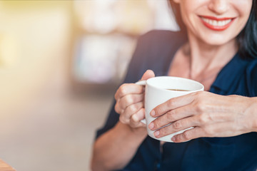 Fresh coffee. Business lady drinking coffee in the office. Copy space on the left side