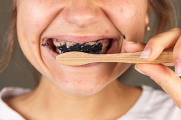 Close-up, a woman is brushing her teeth with black toothpaste, whitening toothpaste, a bamboo...