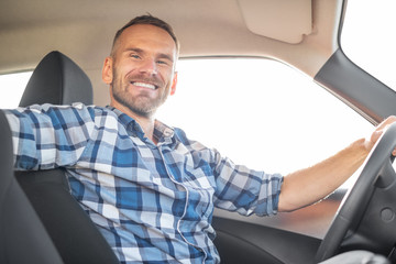 Attractive man driving a car on a clear day. Buying or renting a car.