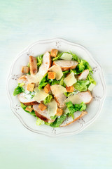 Chicken Caesar salad. Slices of chicken breast, green lettuce, Parmesan cheese, and croutons, shot from above with a place for text