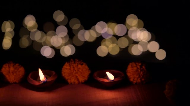 Indian Festive Season. Panning shot of Diwali Diya or oil lamps decorated with flowers burning at dark night. Concept for Indian festival culture and tradition.