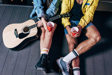 Fototapeta na wymiar cropped view of boyfriend and girlfriend holding plastic cups in night city