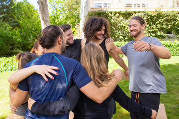 Cheerful young people hugging outdoor. Smiling young men and women in sportswear gathering together in park for yoga practice. Yoga concept