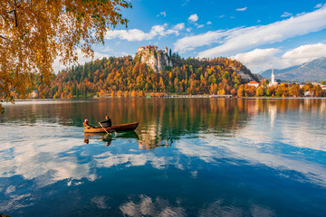 Autumn scenery on Bled lake, Slovenia. Romantic couple sailing by boat
