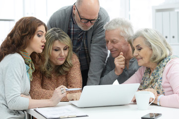 Two senior couples talking with consultant while sitting at table