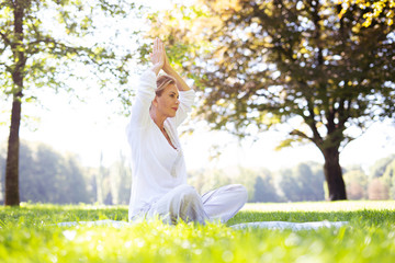 Positive Frau im mittleren Alter macht Meditationsübungen im Park 