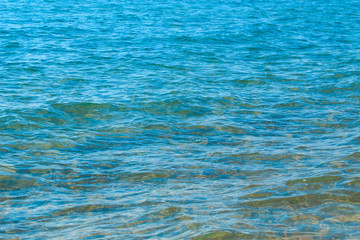 Clear water texture in blue and orange. Background of the ocean and the sea backlit by the sun. Soft waves. Natural water